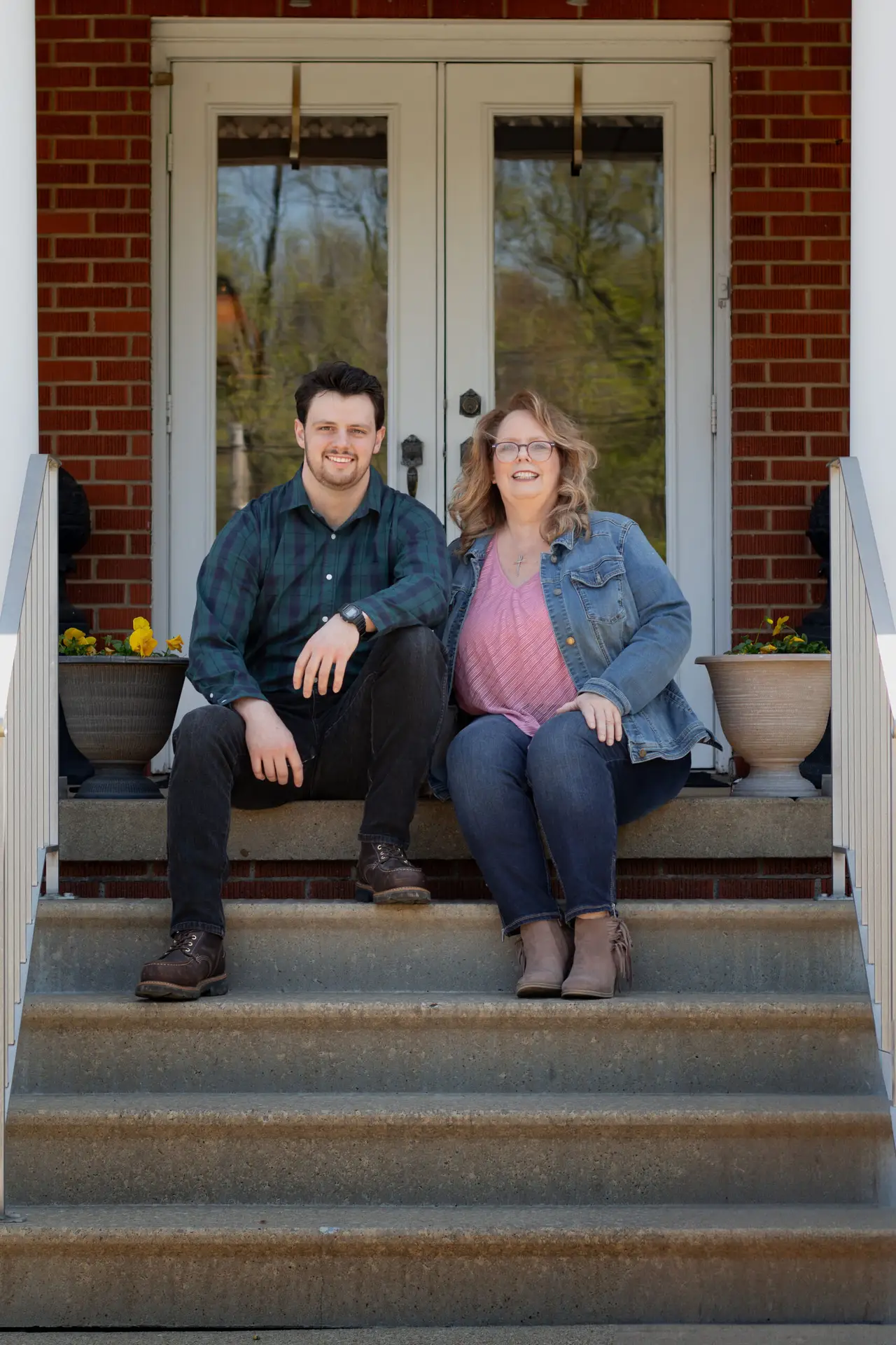 Jake and Meghan of Botkin Restoration sit on the steps of a newly renovated home.