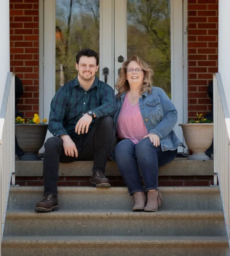 Jake and Meghan of Botkin Restoration sit on the steps of a newly renovated home.